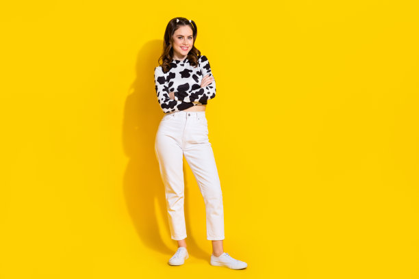 漂亮自信的女孩全身照片穿牛皮衬衫手臂交叉空空间孤立的黄色背景图片下载