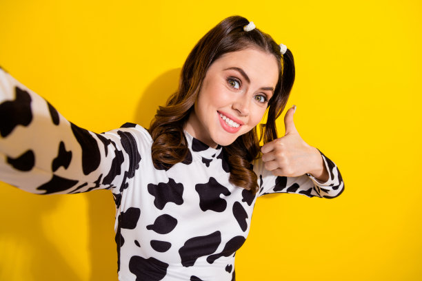 照片上开朗积极的女孩穿着牛皮衬衫，竖起大拇指录制视频视频博客孤立的黄色背景图片下载