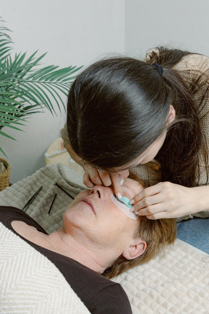 一位女美容师在给女性的睫毛贴膜。图片下载