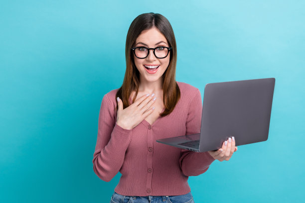 年轻时髦女孩的照片震惊触摸手胸部意外拿笔记本电脑疯狂电子商务交易客户孤立的蓝色背景图片下载