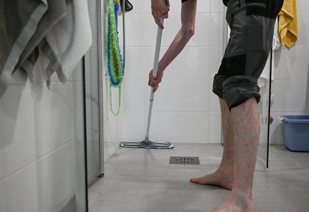 一名男子在卫生间淹水后用拖把擦拭厕所地板图片下载