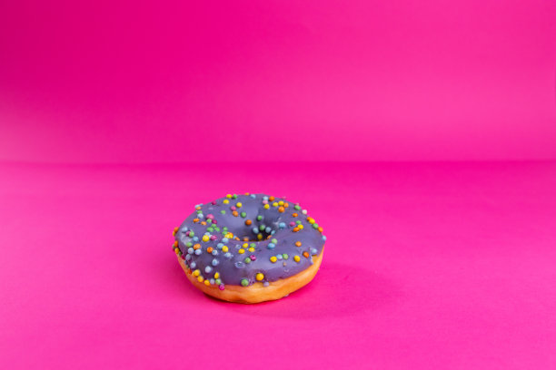 美味的甜甜圈与水果釉和装饰洒落在粉红色的背景-股票照片图片下载
