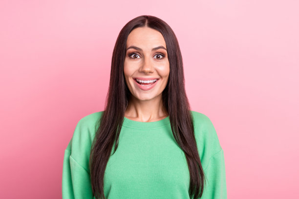 惊讶的可爱的漂亮女人穿着绿色运动衫盯着难以置信的折扣孤立在粉红色背景的照片图片下载