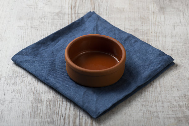 一个空的红色粘土陶瓷碗的模拟照片，深蓝色的亚麻餐巾放在白色的木桌上图片下载