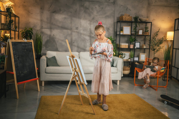 小女孩在家里用毛笔和水彩在帆布架上作画图片下载