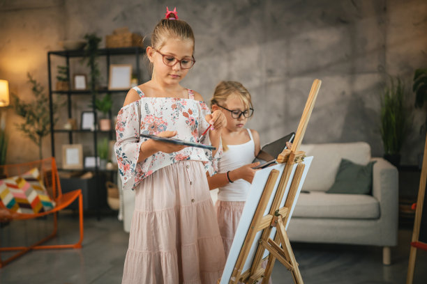 女孩用毛笔在帆布画架上画画，其他女孩用写字板图片下载