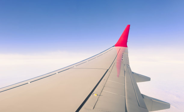 阳光明媚的日子里，从飞机窗口看到的机翼。风景非常好。从飞机窗口鸟瞰云层。飞机的机翼上有蓝天和美丽的云图片下载