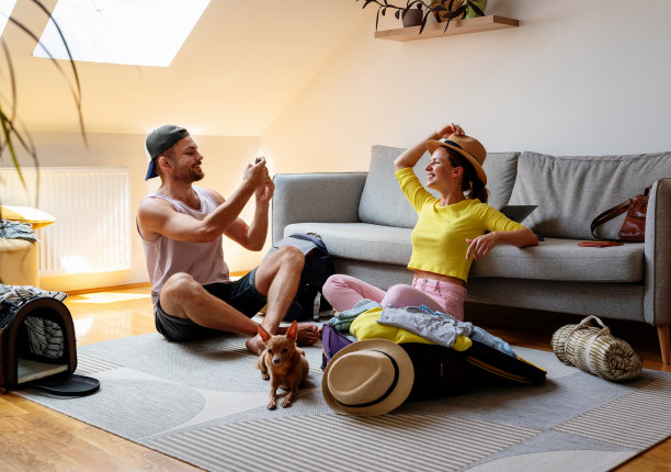 一对年轻夫妇在打包旅行袋时玩得很开心。旅行前的照片回忆。图片下载