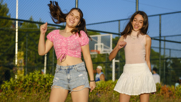 两个十几岁的女孩朋友，一个有点胖，另一个皮肤黝黑，在海边篮球场附近跳舞图片下载