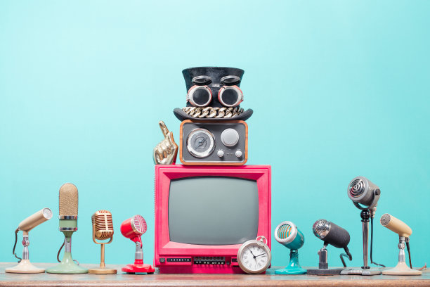 复古麦克风，红色电视，收音机，带护目镜的大礼帽，食指和旧怀表在表前薄荷蓝色背景。复古风格的过滤概念照片图片下载