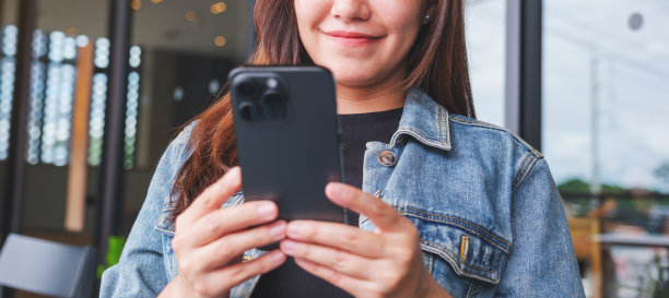 一个女人手持并使用手机的特写图片图片下载