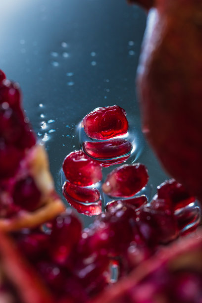 在一个反射表面上的整个和切片石榴的极端特写-库存照片图片下载