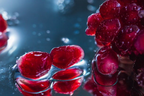 在一个反射表面上的整个和切片石榴的极端特写-库存照片图片下载