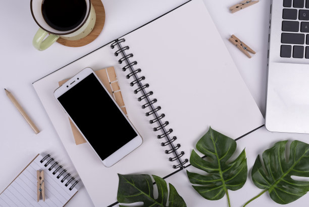 笔记本电脑、智能手机和咖啡杯放在个人记事本里的空白白纸。业务和俯视视图。图片下载