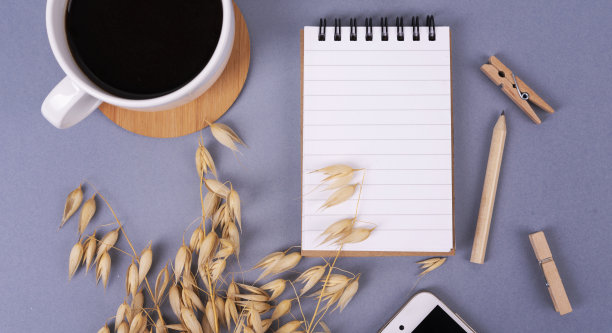 个人记事本里有空白的白纸，办公桌上有智能手机和咖啡杯。业务，设备屏幕和俯视图。图片下载