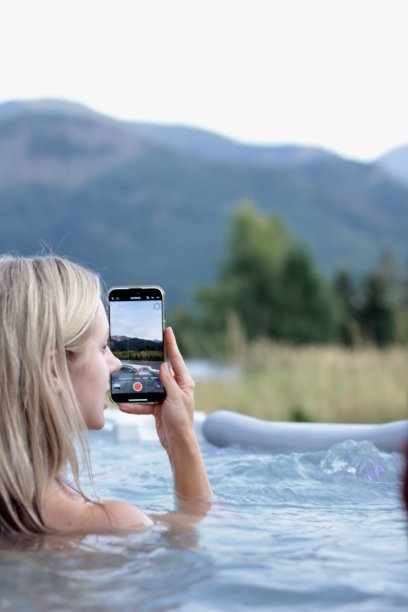 一个女孩在按摩浴缸里洗澡，用手机拍下了大山的照片图片下载