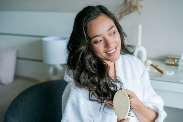 年轻美丽的女人用木梳梳着她的长发。自我保健。图片下载