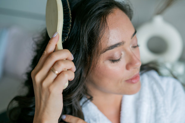 年轻美丽的女人用木梳梳着她的长发。自我保健。图片下载