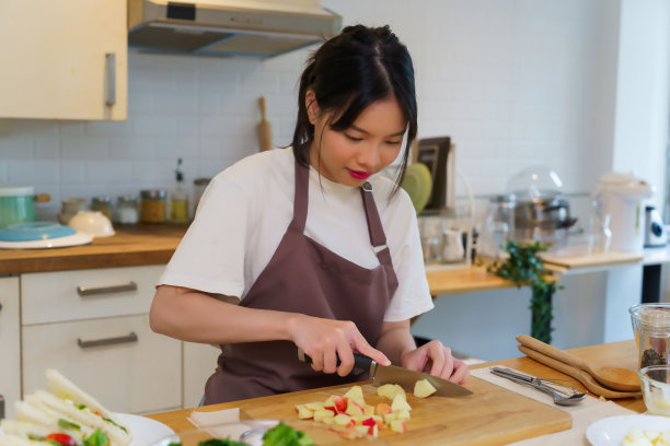 亚洲妇女在菜板上用刀切苹果片，为早餐和沙拉准备水果和蔬菜的原料，同时在厨房营造健康的饮食生活方式图片下载