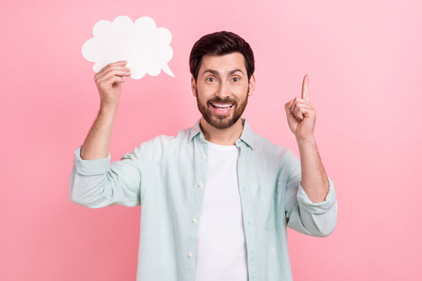 照片中英俊的年轻人手持云漫画形状的手指点起来，穿着时尚的蓝色衣服孤立在粉红色的背景图片下载