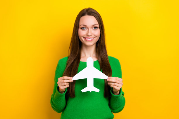 照片中，满意的美女喜气洋洋，双臂抱着黄色背景上孤立的小纸飞机图片下载