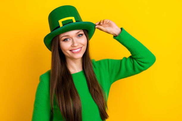 照片中漂亮可爱的女人戴着绿色的毛衣帽子享受着帕特里克日空旷的空间孤立的黄色背景图片下载