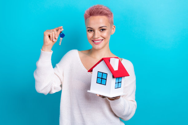 年轻的照片穿着白色长袖套头衫女孩粉色短发hold大楼买了新的家钥匙孤立的海蓝宝石色背景图片下载