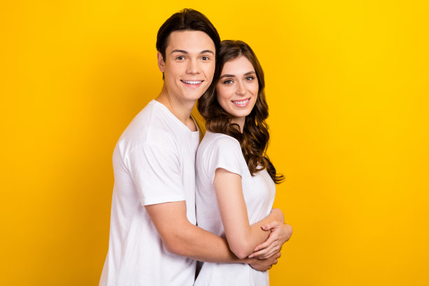 照片中可爱欢快的情侣穿着白色t恤拥抱空旷孤立的黄色背景图片下载