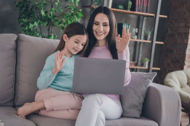 幸福家庭的照片，母亲和小孩坐在舒适的沙发上，用上网本和父亲在现代公寓里远距离交谈图片下载