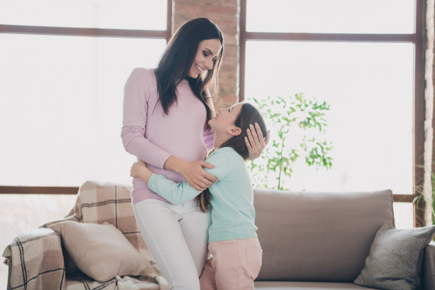 照片中，积极可爱的女儿妈妈穿着休闲装，在公寓房间里微笑着拥抱图片下载