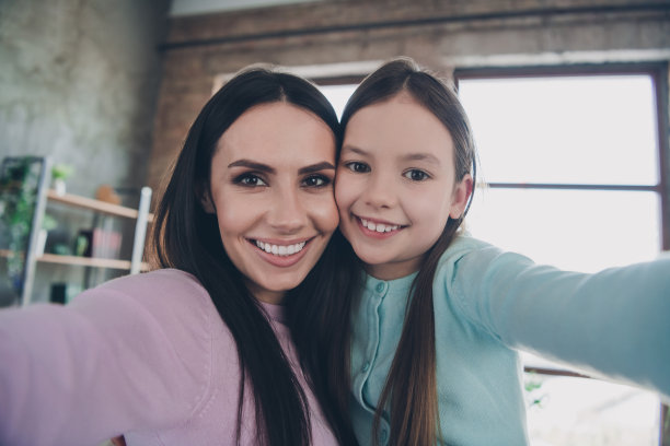 两个开朗可爱的漂亮女孩的照片，妈妈女儿拥抱享受假期春季周末在室内直播图片下载