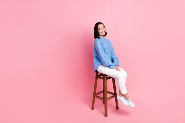 好心情的全尺寸照片满意的好女人穿着针织套头裤坐在椅子上孤立的粉红色背景图片下载