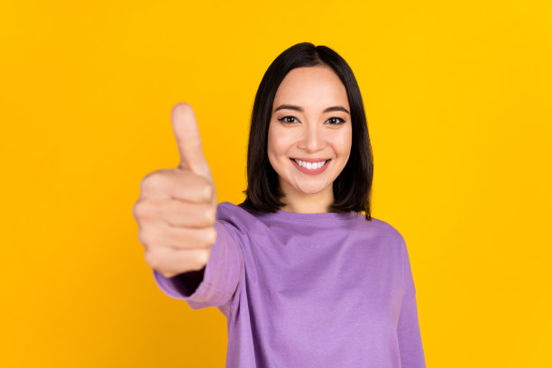 积极的韩国年轻女孩的照片大拇指率很好的反馈给恭维优秀的产品孤立的黄色背景图片下载