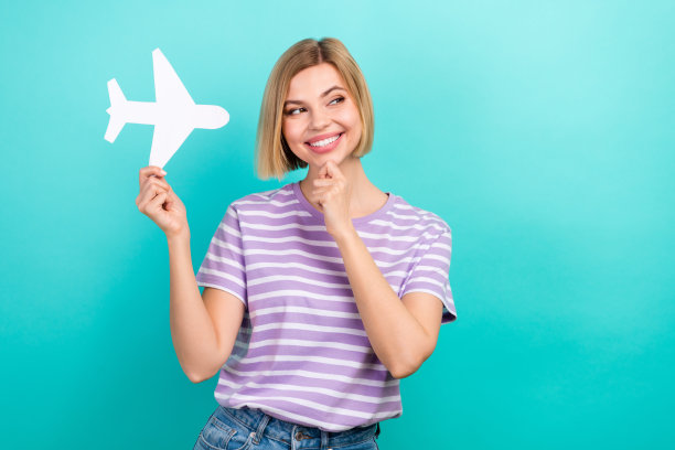 年轻可爱的女人的照片触摸下巴看空空间拿纸飞机头脑选择最好的种族隔离在青色背景图片下载