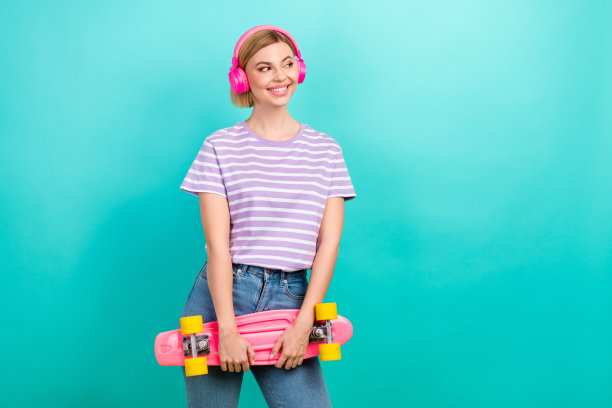 照片广告横幅的时尚女孩享受她的无线苹果耳机pro持有长板看模拟销售孤立的青色背景图片下载