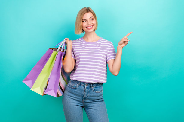 年轻迷人的女孩鲍勃头发的照片直接手指看模拟持有包裹购物中心和孤立的海蓝宝石色背景图片下载