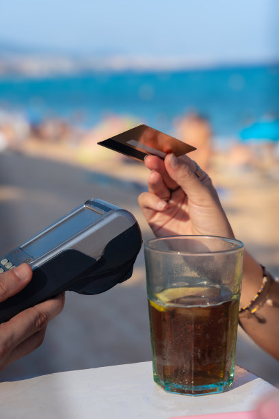 无法辨认的女顾客在餐厅用非接触式信用卡付款。垂直图片下载