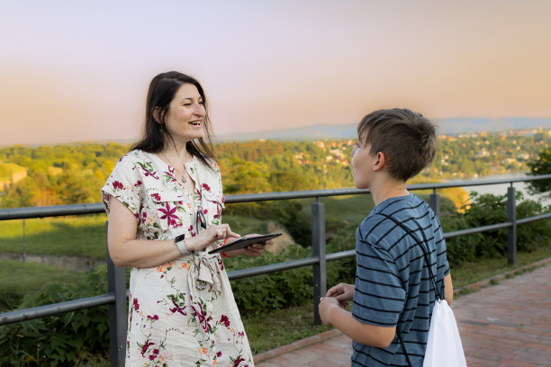 母子二人正在用数码平板电脑进行视频通话和照片信息，并在江边的要塞用在线地图进行定位。旅游观光。城市景观。图片下载