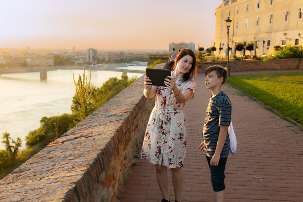 母子二人正在用数码平板电脑进行视频通话和照片信息，并在江边的要塞用在线地图进行定位。旅游观光。城市景观。。佩特罗瓦拉丁城堡诺维萨德图片下载