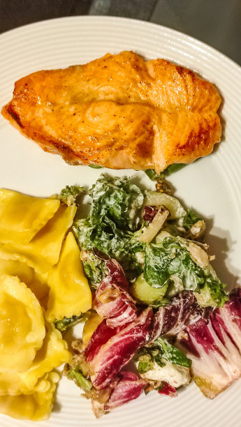 餐盘与烤鲑鱼，意大利饺子，和新鲜的沙拉。垂直移动照片。sstkvertical图片下载