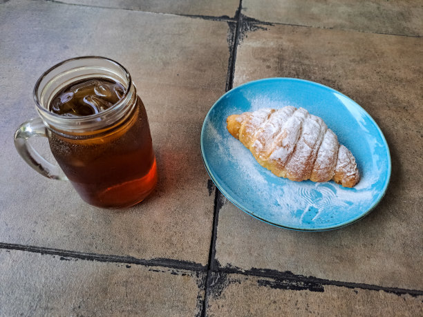 盘子里的新鲜脆皮羊角面包。新鲜的茶冰在杯子里。食物和饮料菜单。图片下载