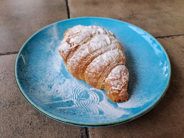 美味的新鲜脆皮羊角面包在盘子里。糕点甜点菜单。图片下载