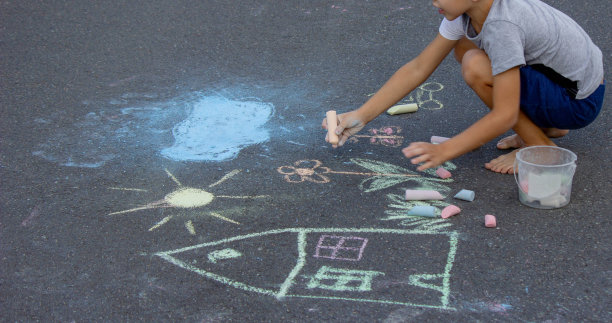 男孩用粉笔在柏油路上画画。有选择性的重点图片下载