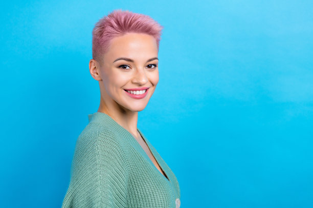 正面可爱女士的侧面照片站在空旷的地方，在蓝色背景上展示了新的明亮发型图片下载