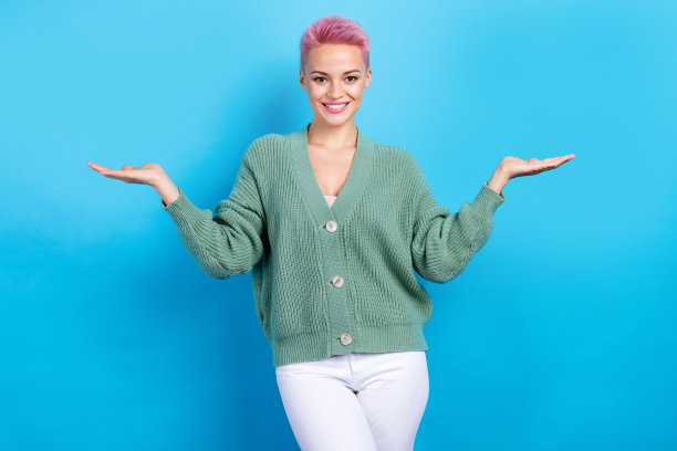 照片正面漂亮开朗的女士穿着时髦的衣服，手臂展示空的空间折扣店孤立的蓝色背景图片下载