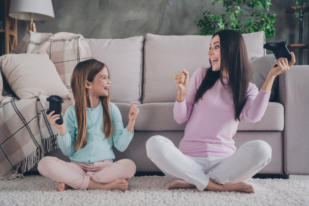 照片中的女儿妈妈穿着休闲的衣服，在公寓房间里高举拳头赢得游戏图片下载