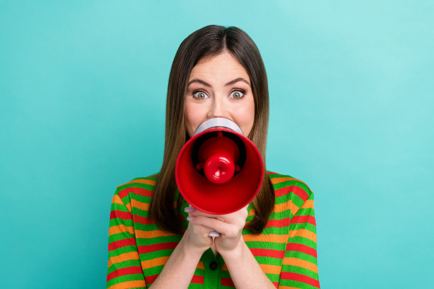 照片中可爱可爱的女人穿着条纹开衫尖叫着牛角孤立的蓝绿色背景图片下载