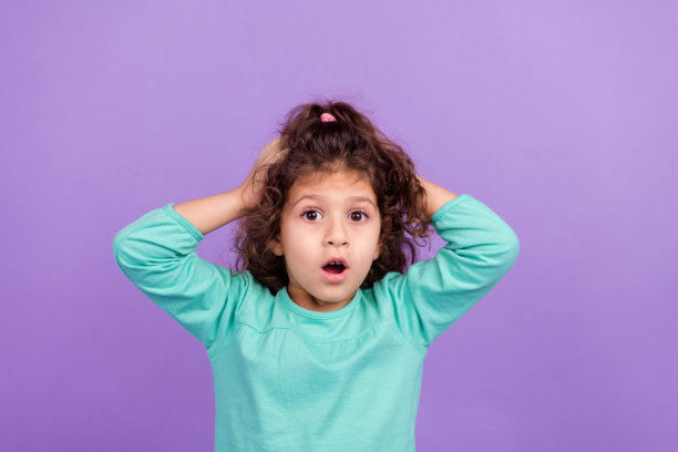 印象深刻的时髦的小孩穿着蓝绿色的衬衫，大眼睛，手臂，头部孤立的紫色背景的照片图片下载