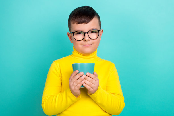 可爱的可爱男孩的照片拿着杯子与柠檬水饮料孤立的海蓝宝石色背景图片下载