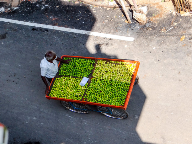 城市里一个人在推车上卖柠檬的高角度照片图片下载